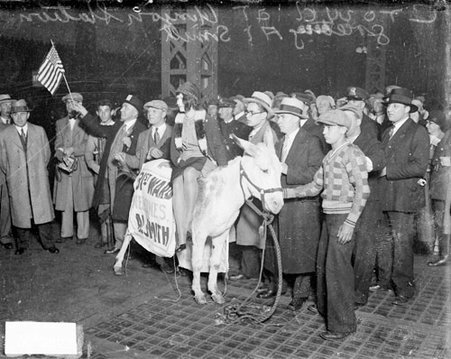 Awaiting the arrival of Alfred E. Smith, young woman sitting atop a donkey whose bridle is held by a boy - Chicago Daily News, Inc.