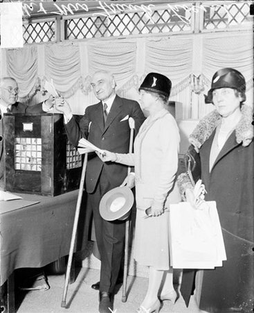 Mr. and Mrs. Frank J. Loesch voting at a voting poll center, an unidentified woman is standing in the foreground - Chicago Daily News, Inc.