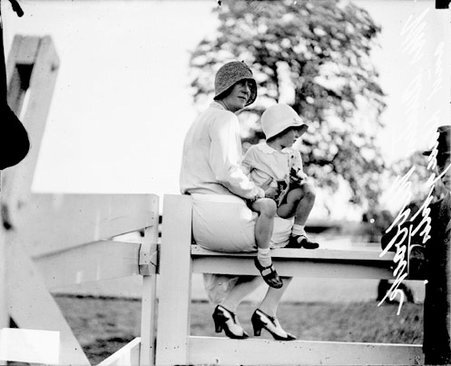 Mrs. Austin Niblack and daughter sitting on a horse track railing at the South Shore Country Club - Chicago Daily News, Inc.