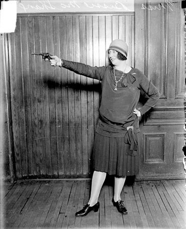 Miss Bessie McShane, policewoman who won pistol shooting tournament, holding a pistol and aiming it to the left of the camera - Chicago Daily News, Inc.
