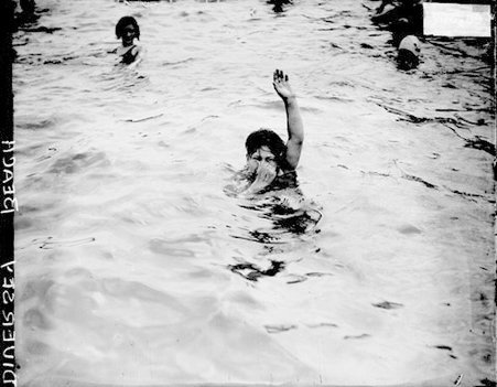 Young women holding up her hand and plugging her nose with her other hand, at Diversey Beach - Chicago Daily News, Inc.