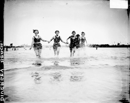 Five young women wearing bathing suits, holding hands, and running in the water at Diversey Beach in Lincoln Park, dark exposure - Chicago Daily News, Inc.