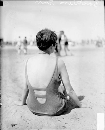 Woman wearing backless suit and sitting on sand at bathing beach in Chicago - Chicago Daily News, Inc.