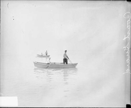 Four Coast Guard members sitting and standing in two rowboats on Lake Michigan, dark exposure - Chicago Daily News, Inc.