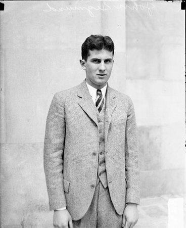 John Sigmund is standing is front of a building looking toward the camera - Chicago Daily News, Inc.