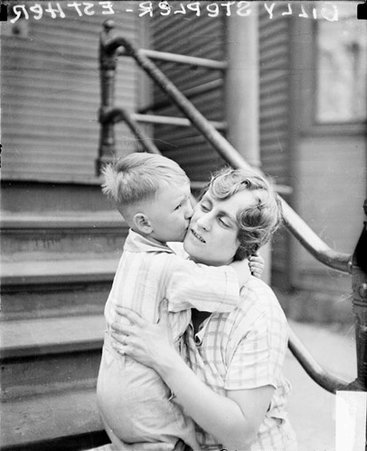 Esther Stepler holding her son Billy, who is kissing her, and sitting on the steps in front of a building - Chicago Daily News, Inc.