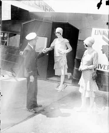 Unidentified woman being assisted out of a Universal Airlines airplane by a man in uniform - Chicago Daily News, Inc.