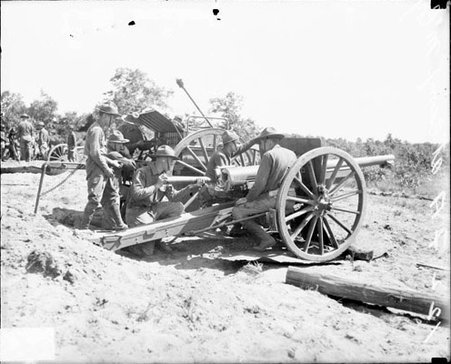 Soldiers from the 122nd Field Artillery regiment loading an artillery cannon on a field - Chicago Daily News, Inc.