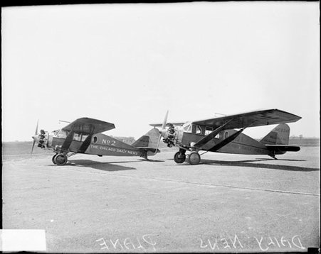 Two Chicago Daily News airplanes sitting on an airfield, viewed at an angle, dark exposure - Chicago Daily News, Inc.