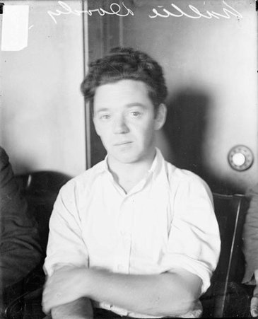 Willie Doody looking toward the camera, sitting in front of a safe in a room - Chicago Daily News, Inc.
