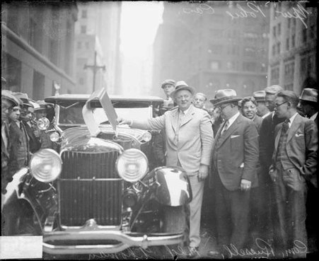 William E. Russell standing next to a new police automobile on a street, lifting the automobile's hood, dark exposure - Chicago Daily News, Inc.
