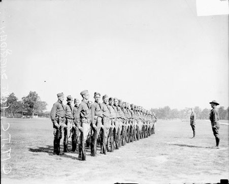 Regiment of soldiers facing to the right of the camera, standing in two rows on a field at Fort Sheridan - Chicago Daily News, Inc.