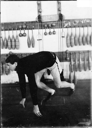 Athlete, unidentified, University of Chicago, crouched in running starter position in a gymnasium - Chicago Daily News, Inc.