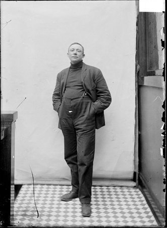 Jockey, John Oaks, standing against a plain backdrop in a stairwell hallway - Chicago Daily News, Inc.