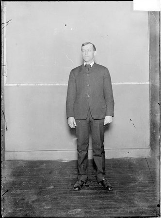 Pugilist, Abe Pollack, wearing a suit, standing against a plain backdrop - Chicago Daily News, Inc.