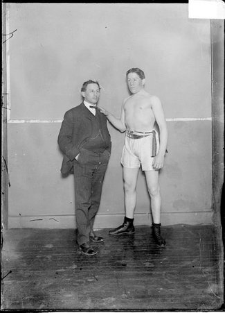 Pugilist, Jack O'Keefe, standing with an unidentified man against a plain wall - Chicago Daily News, Inc.