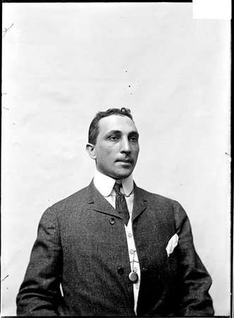 Wrestler, L. Leon, looking to his left, sitting against a plain backdrop - Chicago Daily News, Inc.