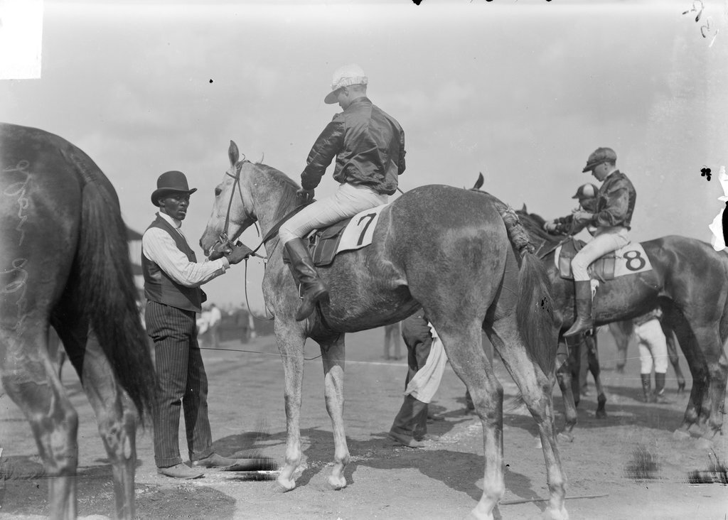 Racehorse, Don Domo, with jockey mounted, being attended by an African American handler, Washington Park Race Track - Chicago Daily News, Inc.
