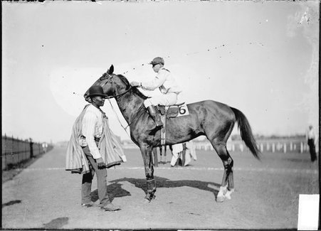 Racehorse, Henry Bert, with jockey mounted, African American handler attending, standing on track, Washington Park Race Track - Chicago Daily News, Inc.