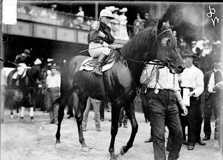 Jockey, W. Knapp, sitting on racehorse Bragg, being led by handler across paddock, Washington Park Race Track - Chicago Daily News, Inc.