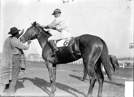 Racehorse, Birch Broom, with jockey mounted, standing in paddock with African American handler - Chicago Daily News, Inc.