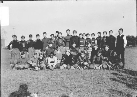 Football team, Hyde Park High School, players posing on an athletic field, player in front with football - Chicago Daily News, Inc.