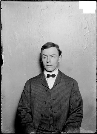 Bowler, Andrew Hall, eyebrow raised, sitting in front of a light colored backdrop - Chicago Daily News, Inc.