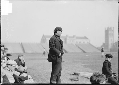 Baseball coach, A. A. Stagg, University of Chicago, standing on Marshall Field with players sitting on ground behind him - Chicago Daily News, Inc.
