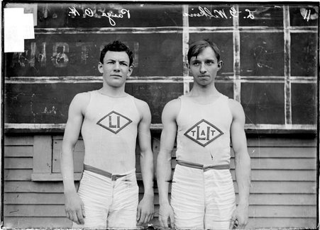 Athletes, L. G. Wilkins and O. H. Paige, standing in front of a chalkboard scoreboard - Chicago Daily News, Inc.