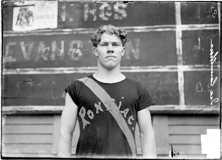 Athlete, Ira Carruthers, Pontiac, standing in front of a chalkboard scoreboard - Chicago Daily News, Inc.