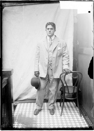 Athlete, W. W. Coe, standing with hand on chair - Chicago Daily News, Inc.