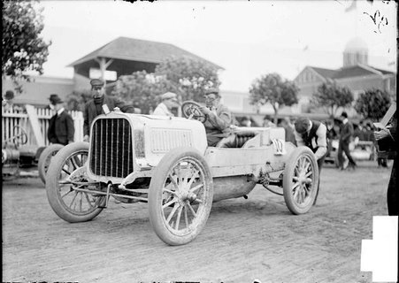 Driver, Herbert Lytle, sitting in car on the track while a mechanic works on car - Chicago Daily News, Inc.