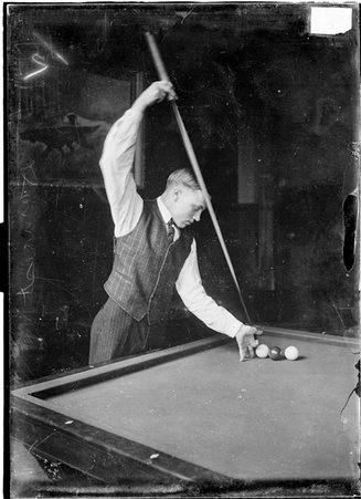 Billiards, Calvin Demarest, playing Carom, holding cue stick vertically, middle finger of bridge hand near ball, shot near corner - Chicago Daily News, Inc.