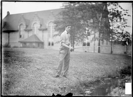 Fly fishing, E. G. Mills, standing on a river bank casting - Chicago Daily News, Inc.