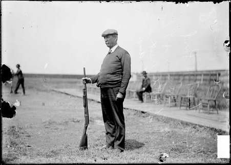 Marksman, Fred H. Lord, standing outdoors, holding rifle with butt of barrel resting on ground - Chicago Daily News, Inc.