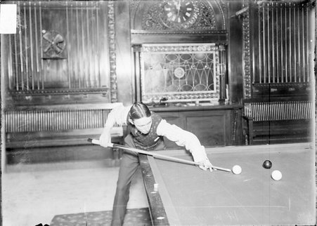 Billiards, H. A. Wright, leaning over a corner pocket, preparing to shoot - Chicago Daily News, Inc.