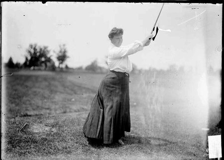 Golfer Mrs. T. E. Donahue, standing on the course holding a golf club above her head at Hinsdale Golf Club in Clarendon Hills, Illinois - Chicago Daily News, Inc.