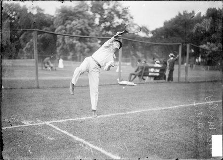 Tennis player E. Morley, following through after serving from behind the baseline on a grass court at the Aztec Tennis Club - Chicago Daily News, Inc.