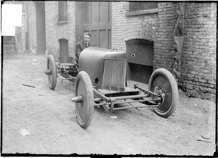 Motorist, Barney Oldfield, sitting in a parked next to a garage - Chicago Daily News, Inc.