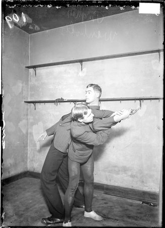 Martial artist G. Weinholtz, performing a Jujitsu maneuver on Albert Pugner, holding a gun in his right hand, in a gymnasium - Chicago Daily News, Inc.