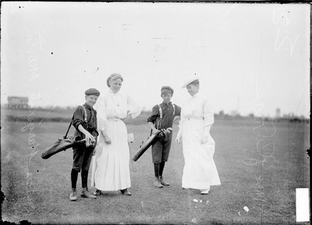 Golfers Margaret Martin and Mrs. J. Page, standing with their caddies on the course at Homewood Country Club in Flossmoor, Illinois - Chicago Daily News, Inc.