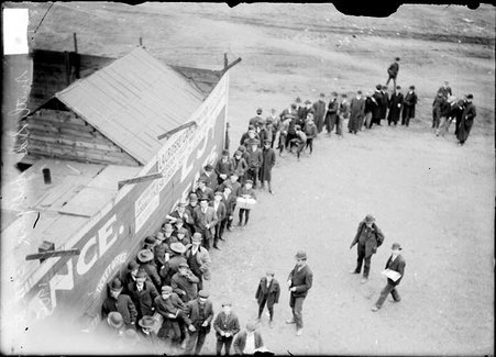 Men and boys standing along a wooden wall outside South Side Park - Chicago Daily News, Inc.