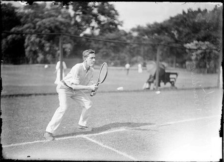 Tennis player C. French, standing with knees bent and racquet in front of his body on a grass court at the Aztec Tennis Club - Chicago Daily News, Inc.