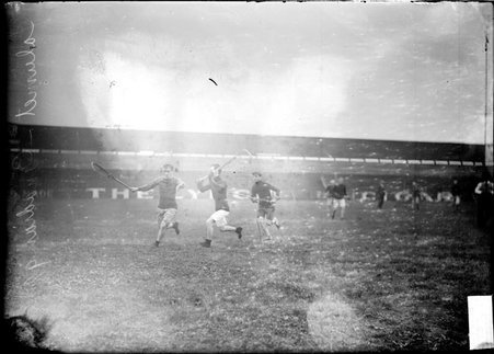 Lacrosse players running to catch the ball, one player has caught the ball and an opponent is approaching him - Chicago Daily News, Inc.