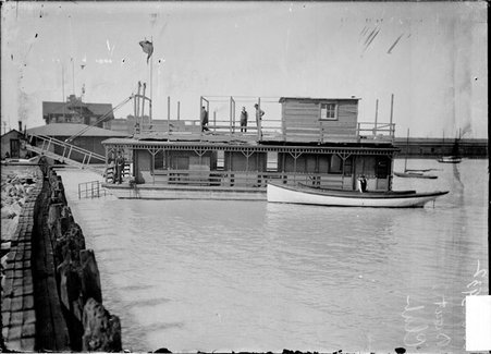 Motorboat club on Lake Michigan at foot of Washington Street, three men standing on top deck of the club, one on left and two on right - Chicago Daily News, Inc.