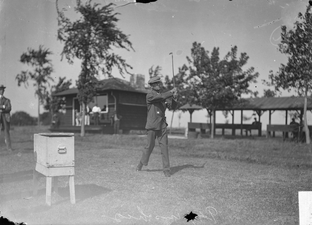 Golfer, W. J. Travis, swinging a golf club on the green, Wheaton Golf Club - Chicago Daily News, Inc.