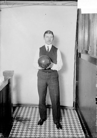 Bowler, A. R. Pudewa, holding a bowling ball, standing against a plain backdrop - Chicago Daily News, Inc.
