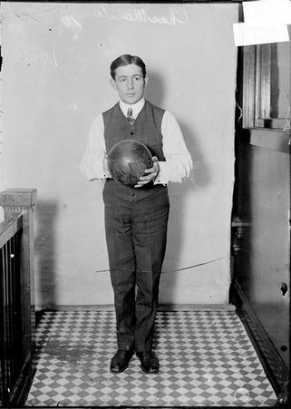Bowler, Charles Mountain, holding a bowling ball, standing against a plain backdrop - Chicago Daily News, Inc.