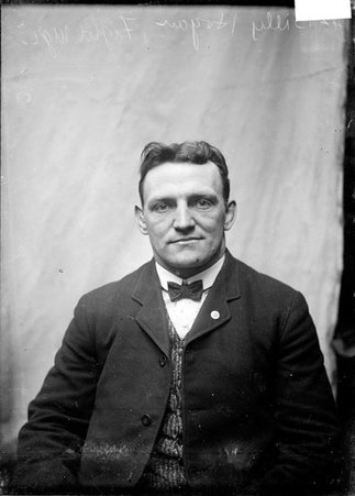 Pugilist, Billy Hogan, sitting in a chair in front of a light colored background - Chicago Daily News, Inc.
