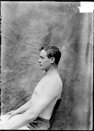 Pugilist, Marvin Hart, sitting in a chair in front of a plain backdrop - Chicago Daily News, Inc.